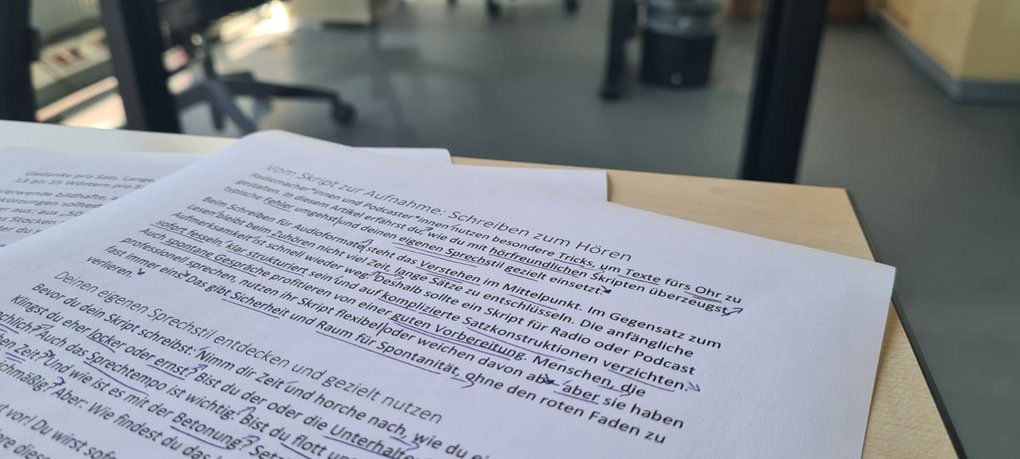 Ausgedrucktes Radioskript mit deutschem Text liegt auf Schreibtisch